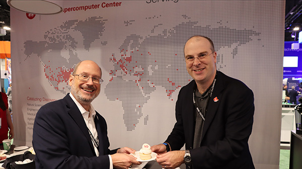 Dave Hudak and Alan Chalker holding a Open OnDemand 10th anniversary cupcake at SC23 in Denver, Colorado