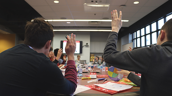 Two individuals raising their hands during team building activitiy