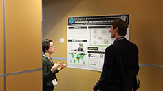 Two individuals interact in front of a poster in the poster session at the Spring 2023 SUG conference