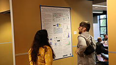 Two individuals interact in front of a poster in the poster session during lunch at the Spring 2023 SUG conference