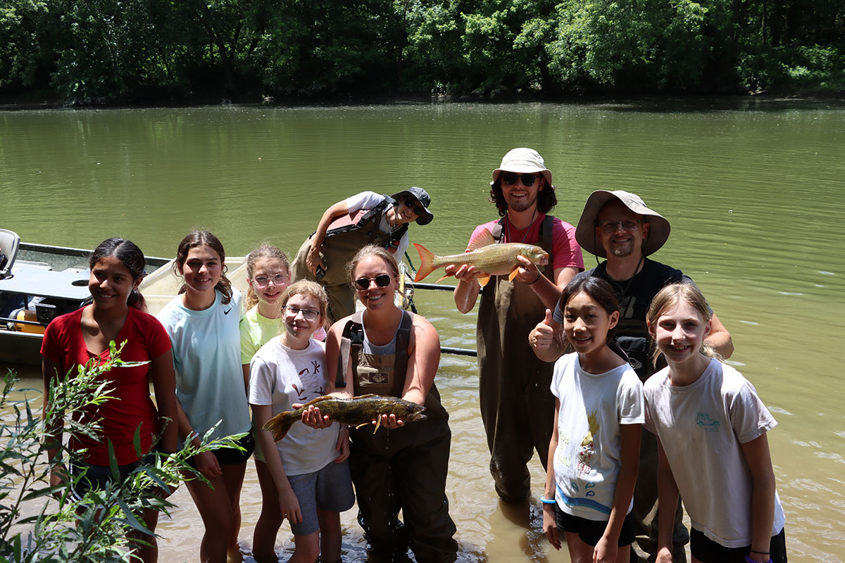 A group of people pose in front of a creek.