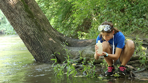 YWSI student collecting a water sample for Batelle-Darby creek.