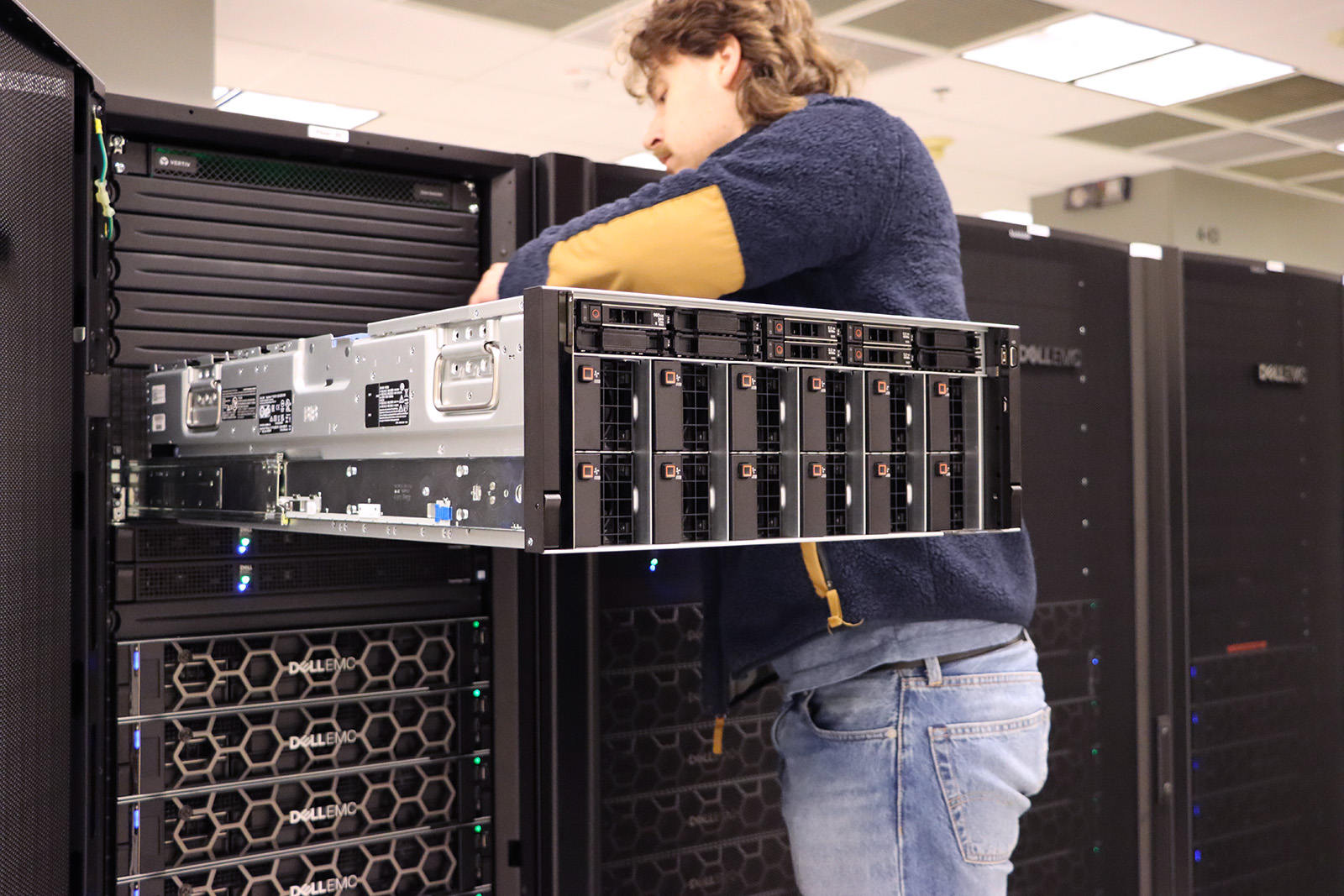 Staff member Frantisek Bartik works on the test node of Ascend, installed inside an open slot in the Pitzer cluster.