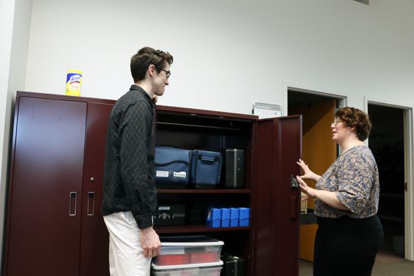 Liz and Nicholas discuss work in front of storage cabinets
