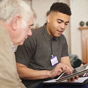 A social worker sits across from a person and interacts with a tablet